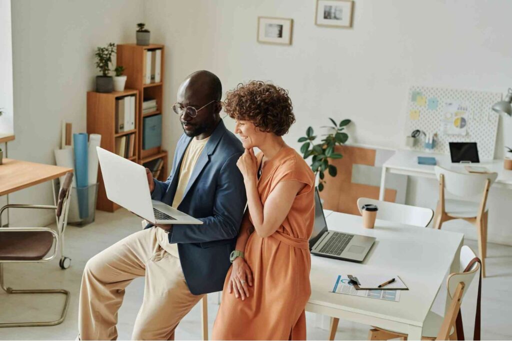 Coworkers discussing project on laptop in modern office