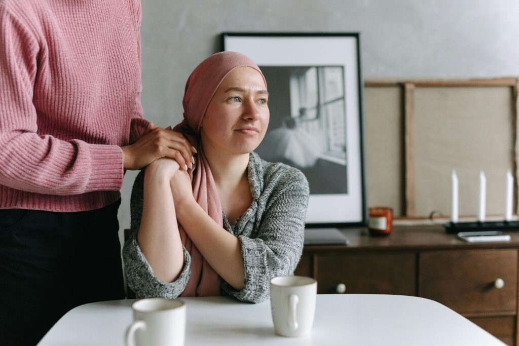 Woman in headscarf comforted by friend at table