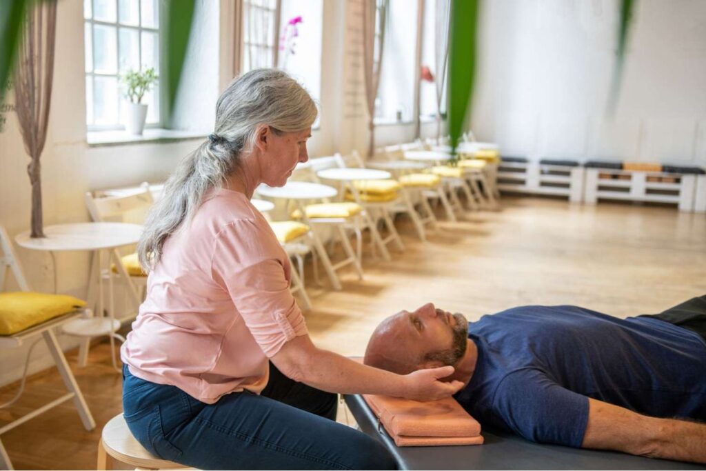 Therapist performing head therapy on relaxed man.