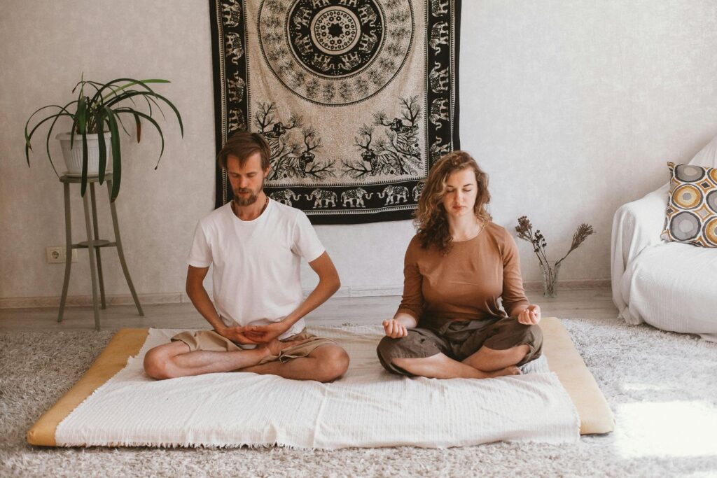 Couple practicing meditation indoors on yoga mats