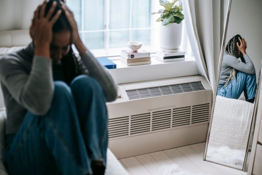 Person sitting stressed near mirror indoors