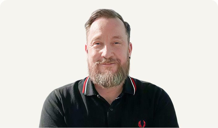 Smiling man with beard wearing black polo shirt