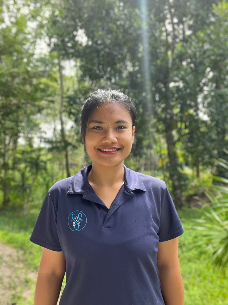 Woman smiling in forest wearing navy polo