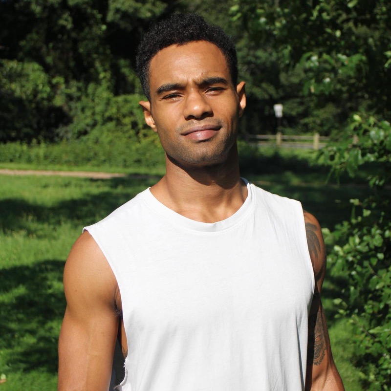 Man in sleeveless shirt standing in sunny park